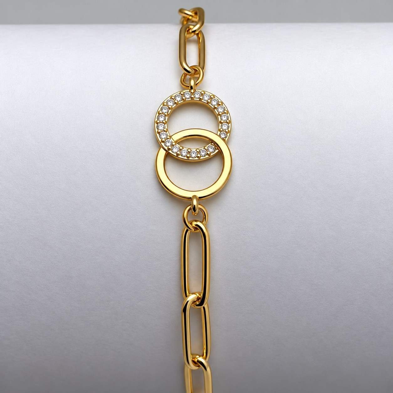 Gold chain bracelet with interlocking circle charms and crystal accents on white background.