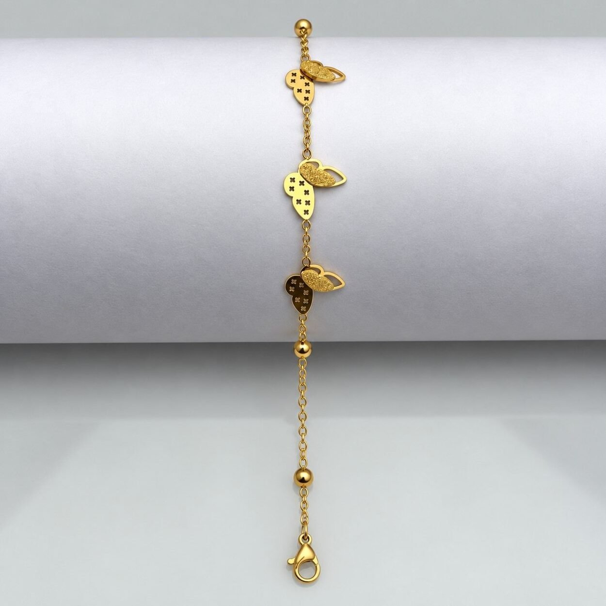Butterfly Charm Bracelet on White 3-100kb Triple butterfly gold charm bracelet with adjustable chain and delicate butterfly motifs.
