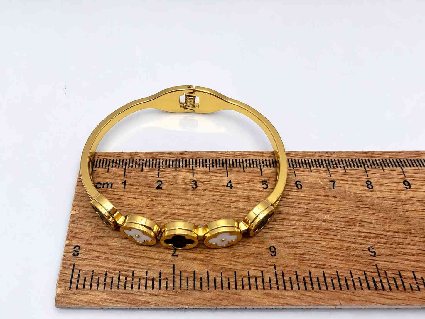 Luxury gold bangle featuring black and pearl clover motifs for women.