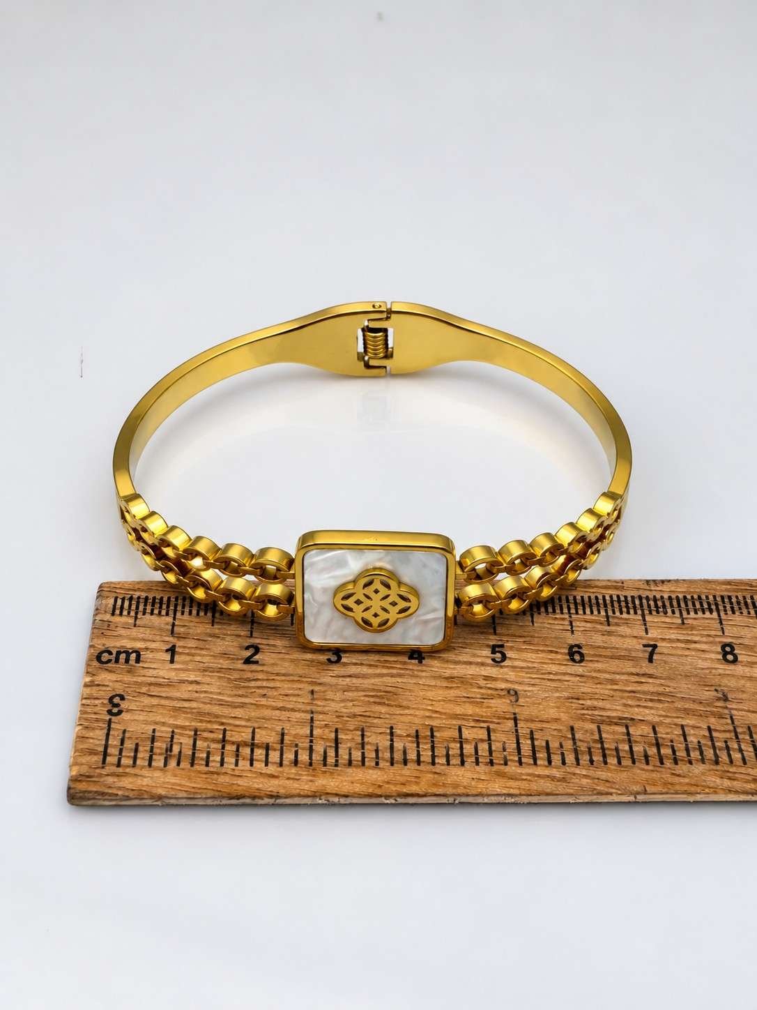SHYNEL golden bangle bracelet with opalescent clover centerpiece and decorative bead detailing